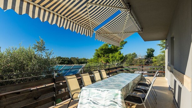 Un patio al aire libre con una mesa cubierta por un mantel estampado, rodeado de sillas.