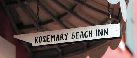 Une enseigne en bois portant l’inscription « ROSEMARY BEACH INN » est suspendue à une chaîne.