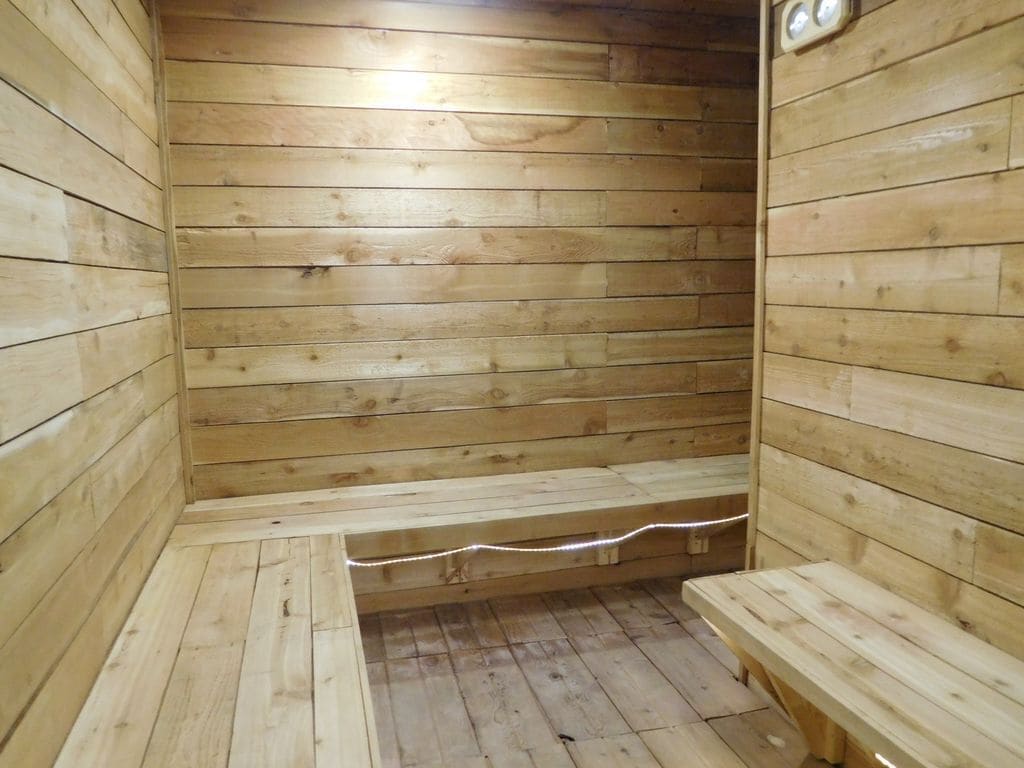 Puisesta laudelankusta rakennettu sauna, jossa on penkit ja seinää pitkin kulkeva laide.