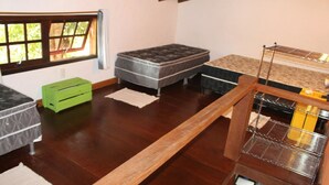 Une pièce avec un plancher en bois, une fenêtre donnant sur un beau paysage, une boîte de rangement verte et un étagère en métal.