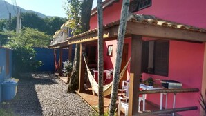 Un bâtiment rouge doté d’une terrasse en bois, d’un hamac et d’une petite table avec des chaises.