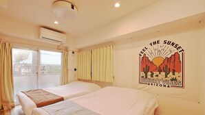 Habitación de hotel con dos camas, un ventanal grande con cortinas, un equipo de aire acondicionado y un mural en la pared que representa un paisaje desértico con el texto "Feel the Sunset Desert Vibes Arizona".