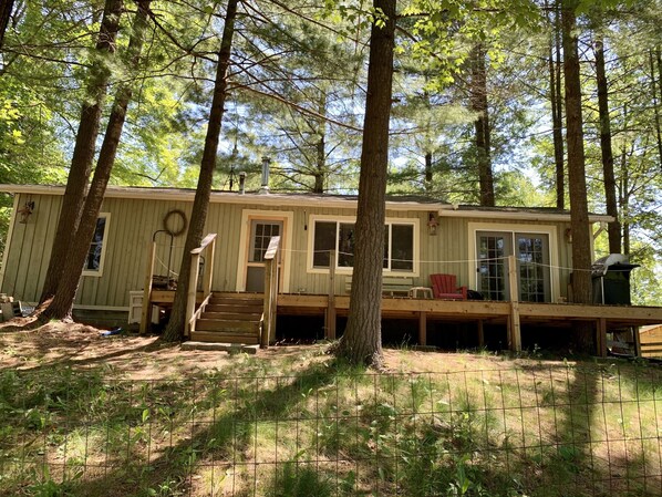A cabin with a deck, a staircase, and a covered porch area.
