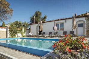 Relax by the serene pool surrounded by lush greenery and flowering plants.