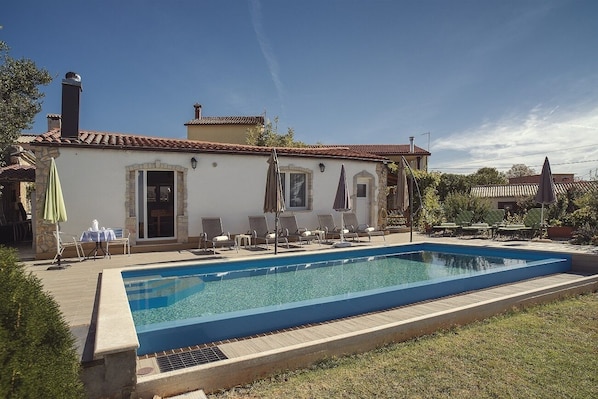 Relax by the pool surrounded by lush greenery and outdoor seating areas.