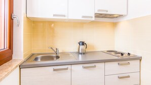 A modern kitchen with white cabinets, a stainless steel sink, a coffee maker, and a built-in induction cooktop. - Apartment 500 meters to beach (Banjole)