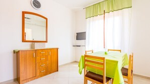 A room with a wooden cabinet, a mirror, a television, a table with a green tablecloth, and a window with curtains. - Apartment 500 meters to beach (Banjole)