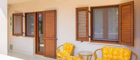 A balcony with wicker furniture and wooden shutters.