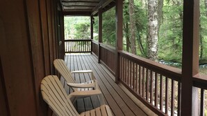 A wooden deck with two Adirondack chairs facing a forested area. - Doig Cabin: Support a great cause while on vacation! (Government Camp)