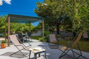 An outdoor patio with a pergola, lounge chairs, a table, and a small table with a book. - Fully fenced holiday home, your pet is also welcome (Rakalj)