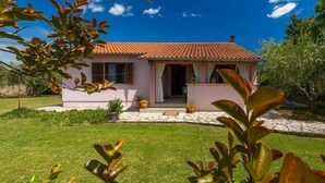 A single-story house with a red-tiled roof, a front porch, and a garden with potted plants. - Fully fenced holiday home, your pet is also welcome (Rakalj)