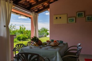 A covered outdoor dining area with a table set for two, chairs, and a view of the garden. - Fully fenced holiday home, your pet is also welcome (Rakalj)