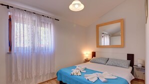 Une chambre à coucher comprenant un lit, une table de chevet, une commode, un miroir et une fenêtre avec des rideaux.