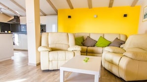 A living room with a yellow wall, a beige sofa set, and a white coffee table.