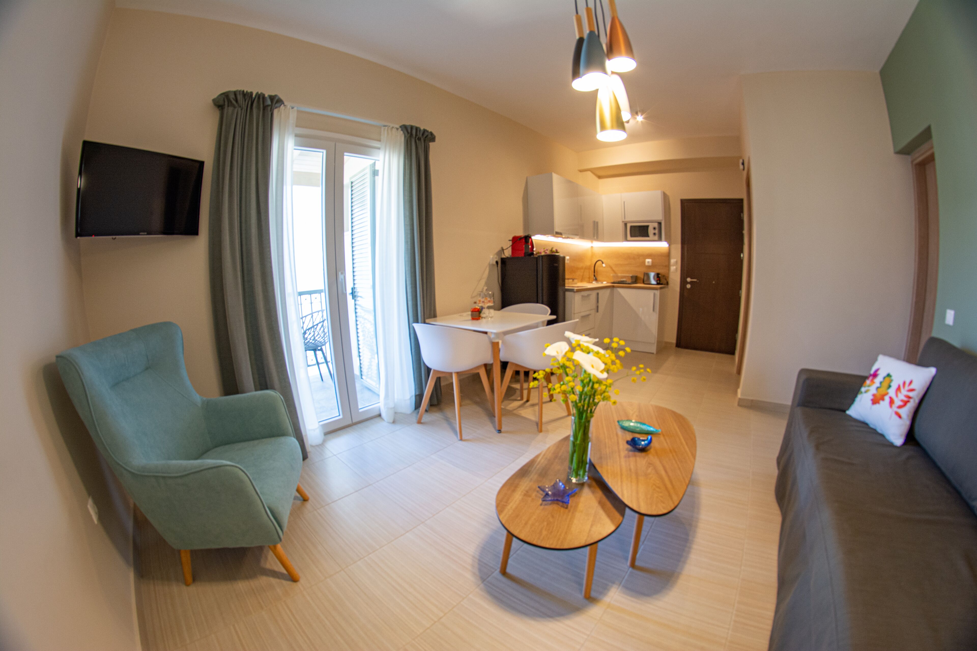 Una sala de estar moderna con un sofá, una mesa de comedor y un televisor montado en la pared.