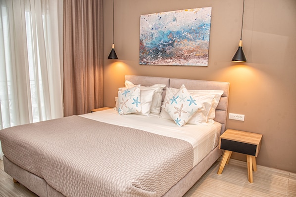 A bedroom with a large bed, two bedside lamps, a nightstand, and a painting on the wall.