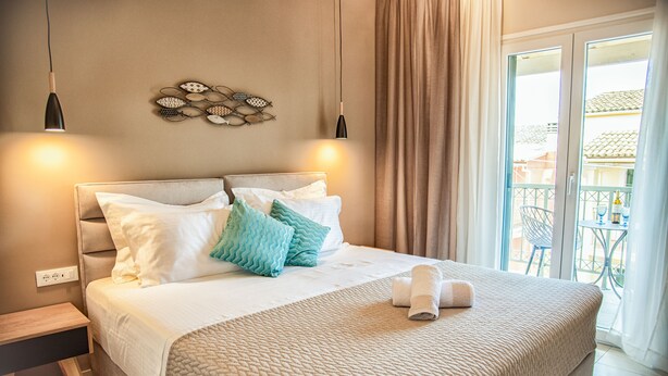 Una cama bien tendida con cubrecama acolchado, una mesita de noche y una lámpara fijada a la pared.