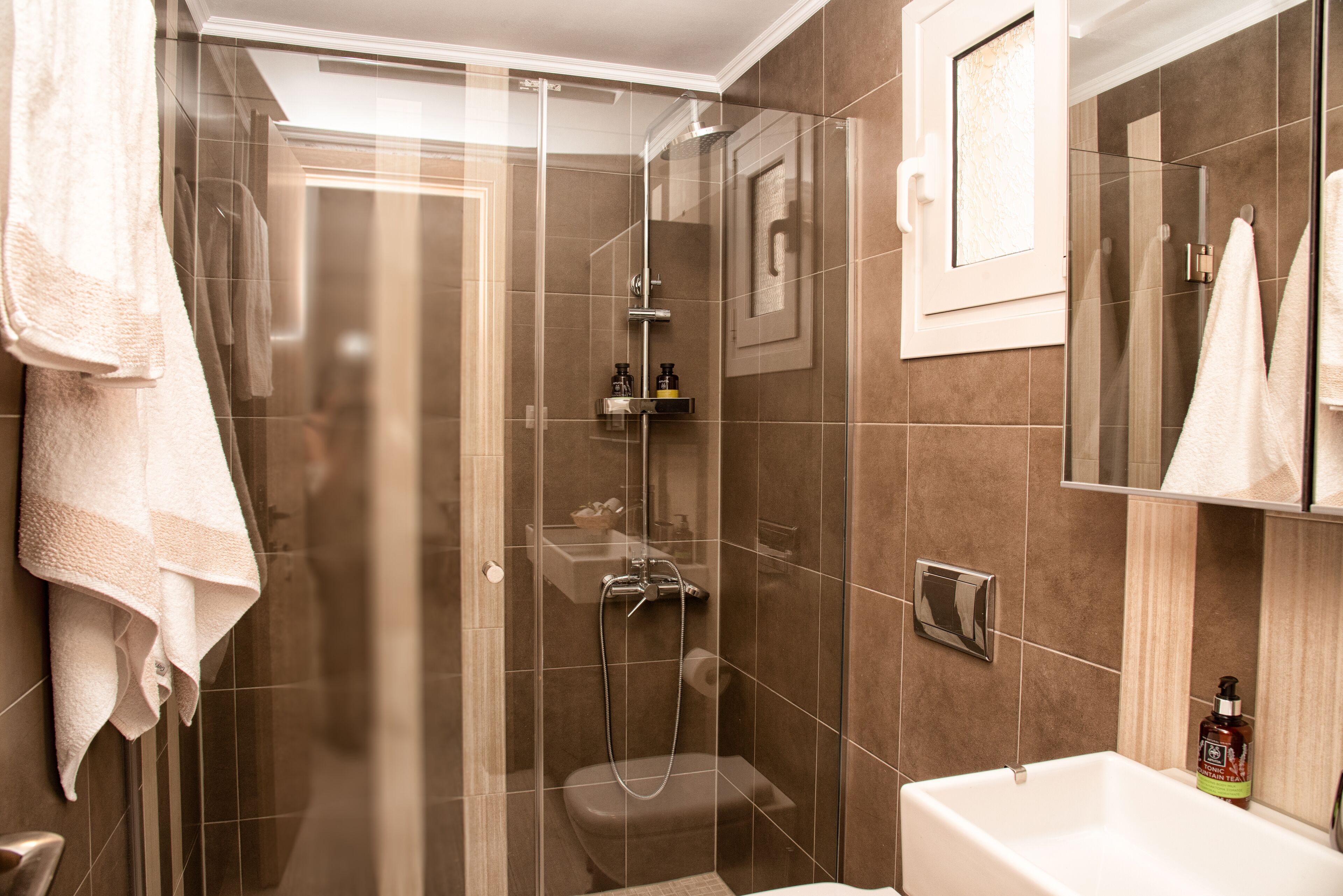 Un baño moderno con ducha acristalada, inodoro y lavamanos.