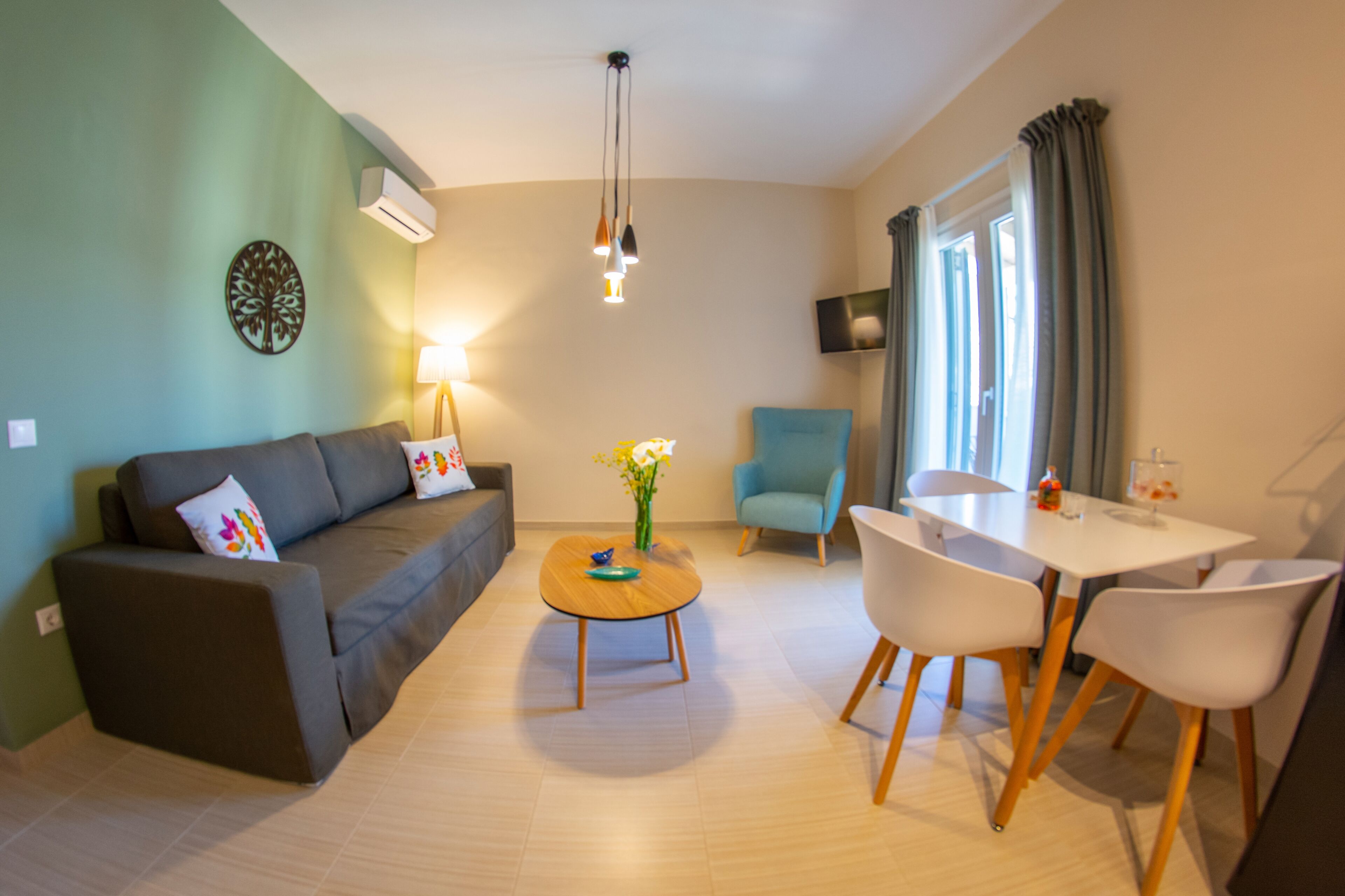 A modern living room with a sofa, a coffee table, a dining table with chairs, a TV, and a window with curtains.