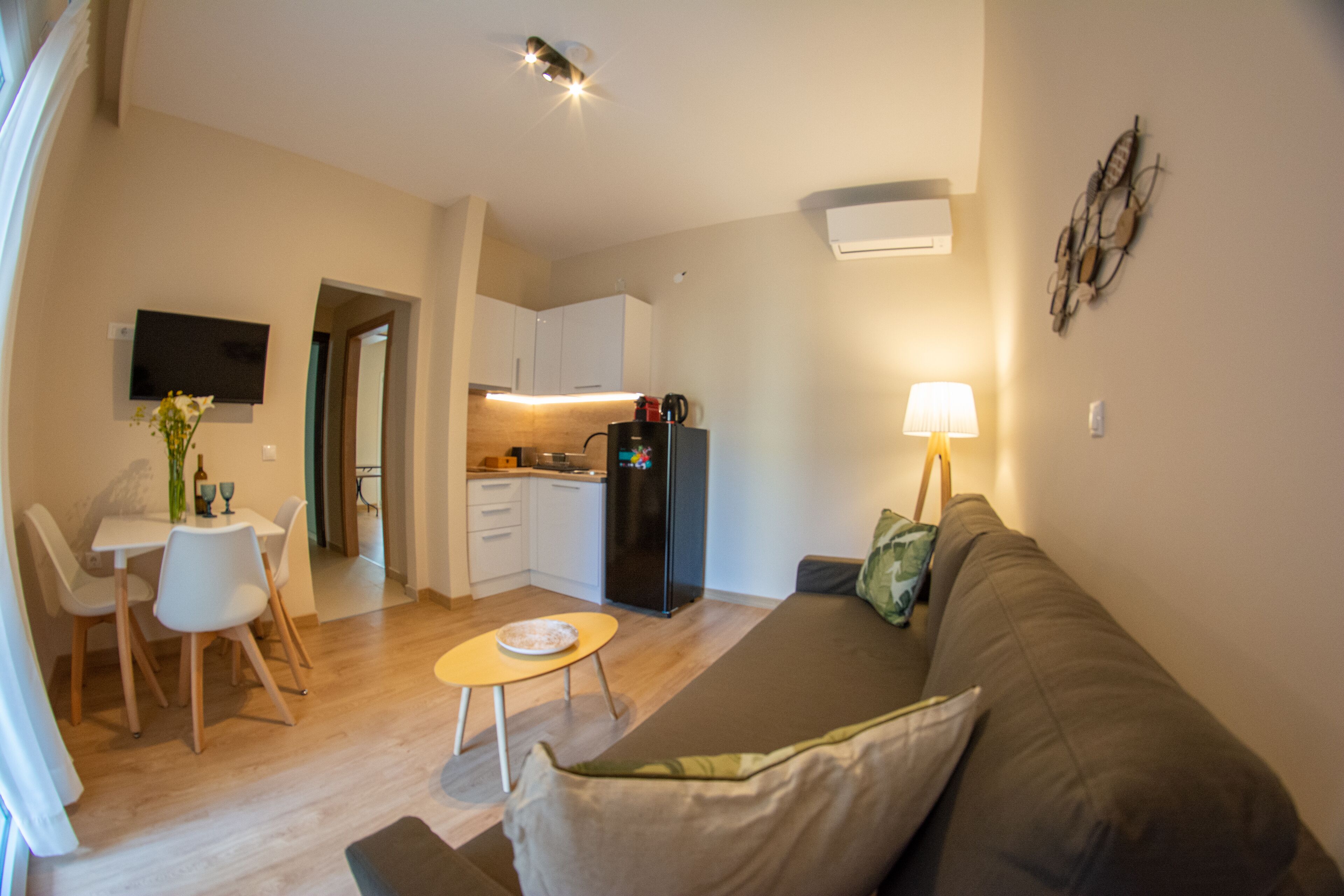 Un espace de vie compact comprenant un coin repas, une kitchenette et un canapé avec une lampe.