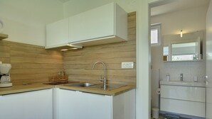 Een moderne keuken met een houten achterwand, witte kasten en een RVS-spoelbak.