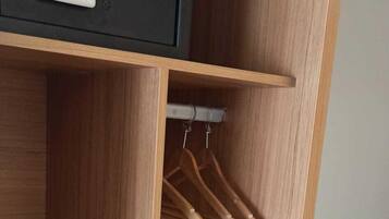 Een houten garderobe met een geïntegreerde kluis, een kledingroede en een plank met schoenen.