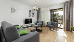 A modern living room with a grey sofa, a black coffee table, a TV, and patterned armchairs. - Newly renovated Apartment with WiFi and BBQ (Pula)