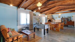 Una sala de estar acogedora con mesa de fútbol, muebles de madera y una zona de cocina.