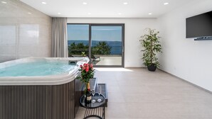 A modern indoor space with a hot tub, a table with a bottle and glasses, and a potted plant. - Luxurious Villa ADA with hot tub, sauna, gym, infinity pool, sea views! (Omiš)