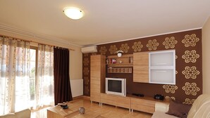 A modern living room with a sofa, TV, wooden cabinet, and decorative wall patterns. - Air-conditioned flat with jacuzzi, sun loungers, Wi-Fi (Maruzini)
