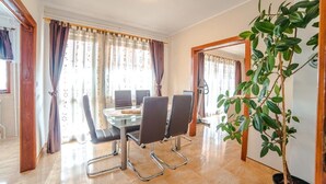 A dining area with a round table, four chairs, and a potted plant. - Air-conditioned flat with jacuzzi, sun loungers, Wi-Fi (Maruzini)
