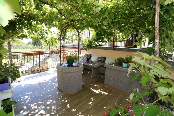 Un espace extérieur aménagé, abrité et doté de jardinières en pierre et d’une rambarde en métal.