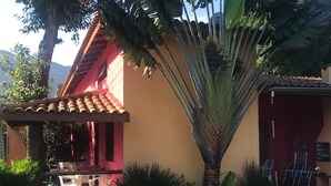 Ein Gebäude mit rotem Dach und einer überdachten Terrasse mit weißen Plastikstühlen.