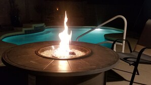 A circular fire pit with a pool in the background. - *** GORGEOUS DESERT GETAWAY WITH HEATED  POOL NEAR THE DUKE GOLF COURSE*** (Maricopa)