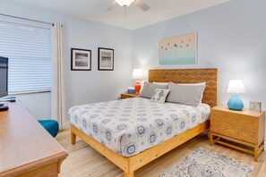 A bedroom with a bed, bedside tables, a desk, and a window with blinds.