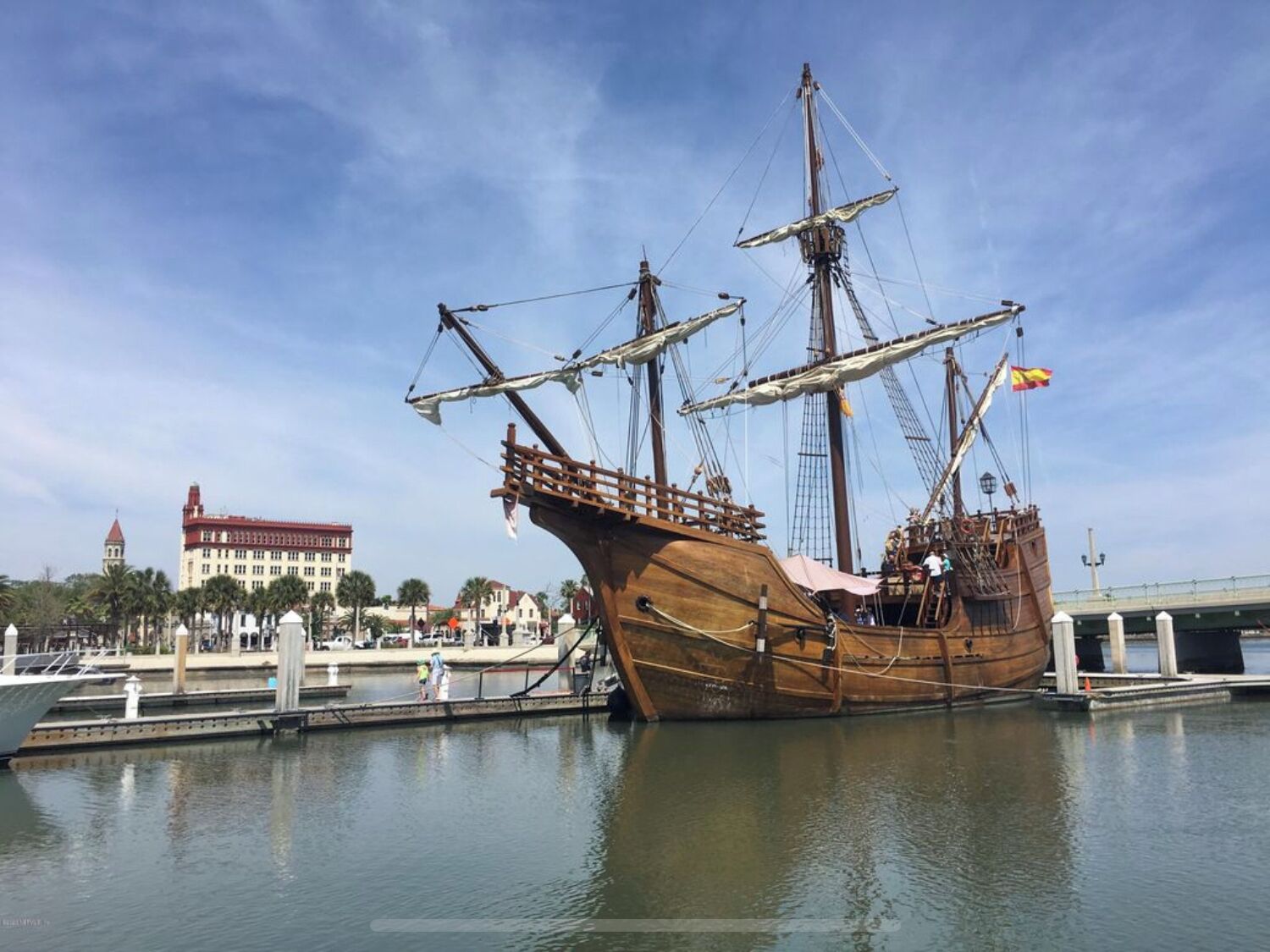 Un grand navire en bois était amarré dans une marina, avec un bâtiment visible en arrière-plan.