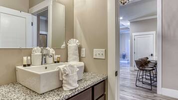 A modern bathroom with a large sink, mirror, and towel rack.