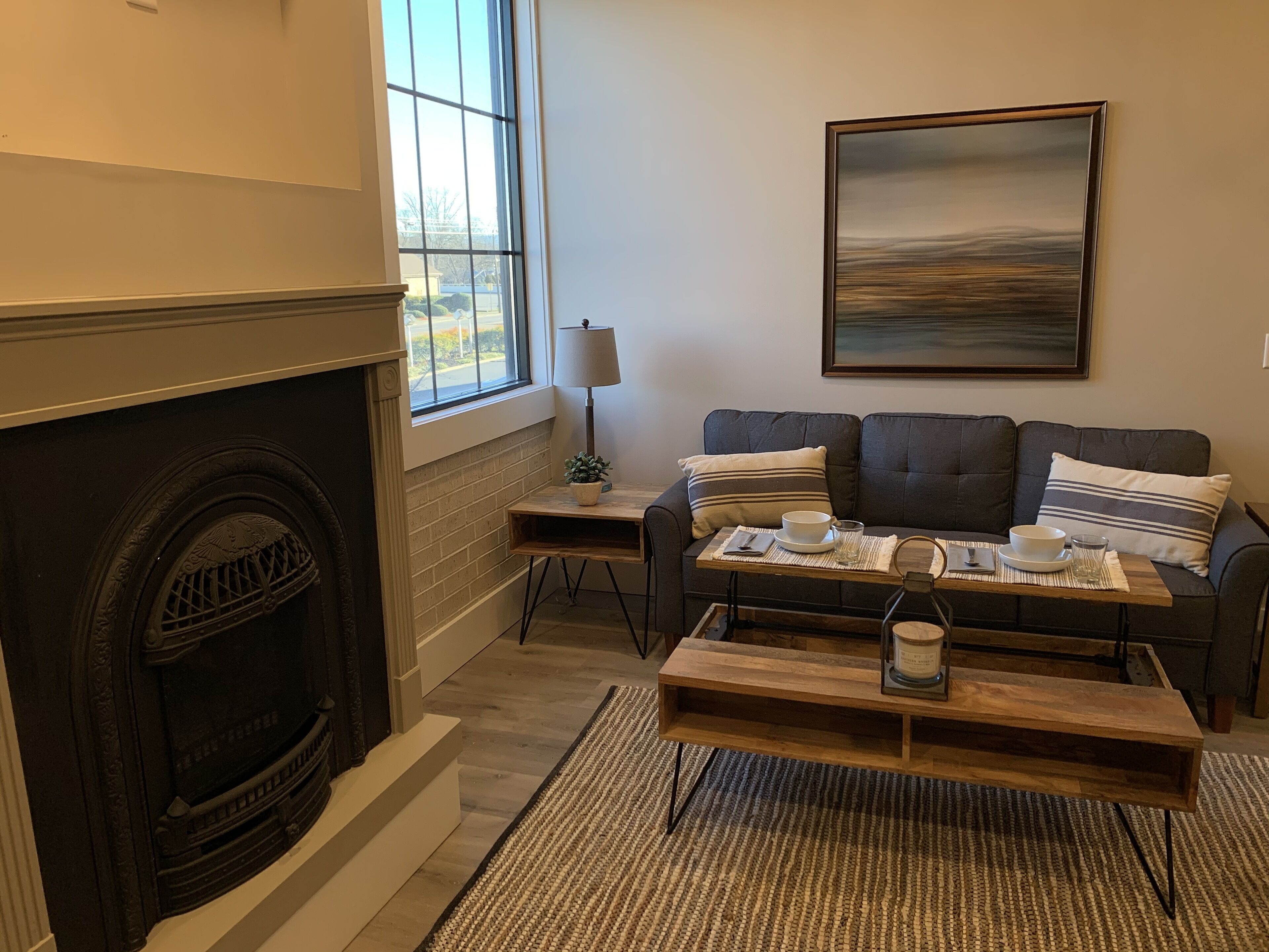 A cozy living room with a fireplace, a sofa set, a coffee table, and a painting on the wall.
