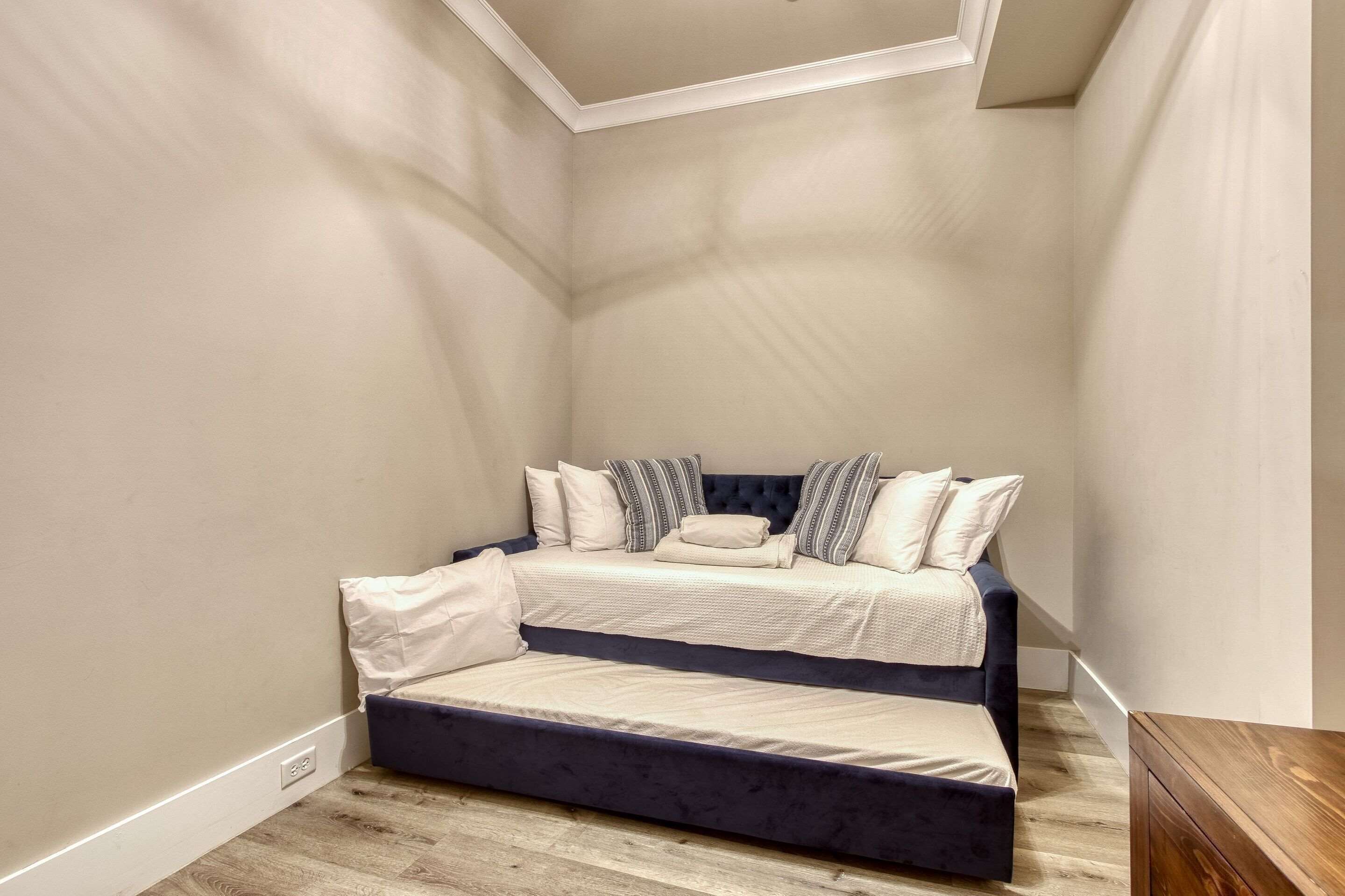 A bedroom with a bed, a wooden floor, and a ceiling with a recessed light fixture.