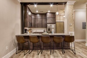 A kitchen with a central island, dark wooden cabinets, and bar stools. - The Historic Central Hotel, a New Hotel Collection Property (Sevierville)