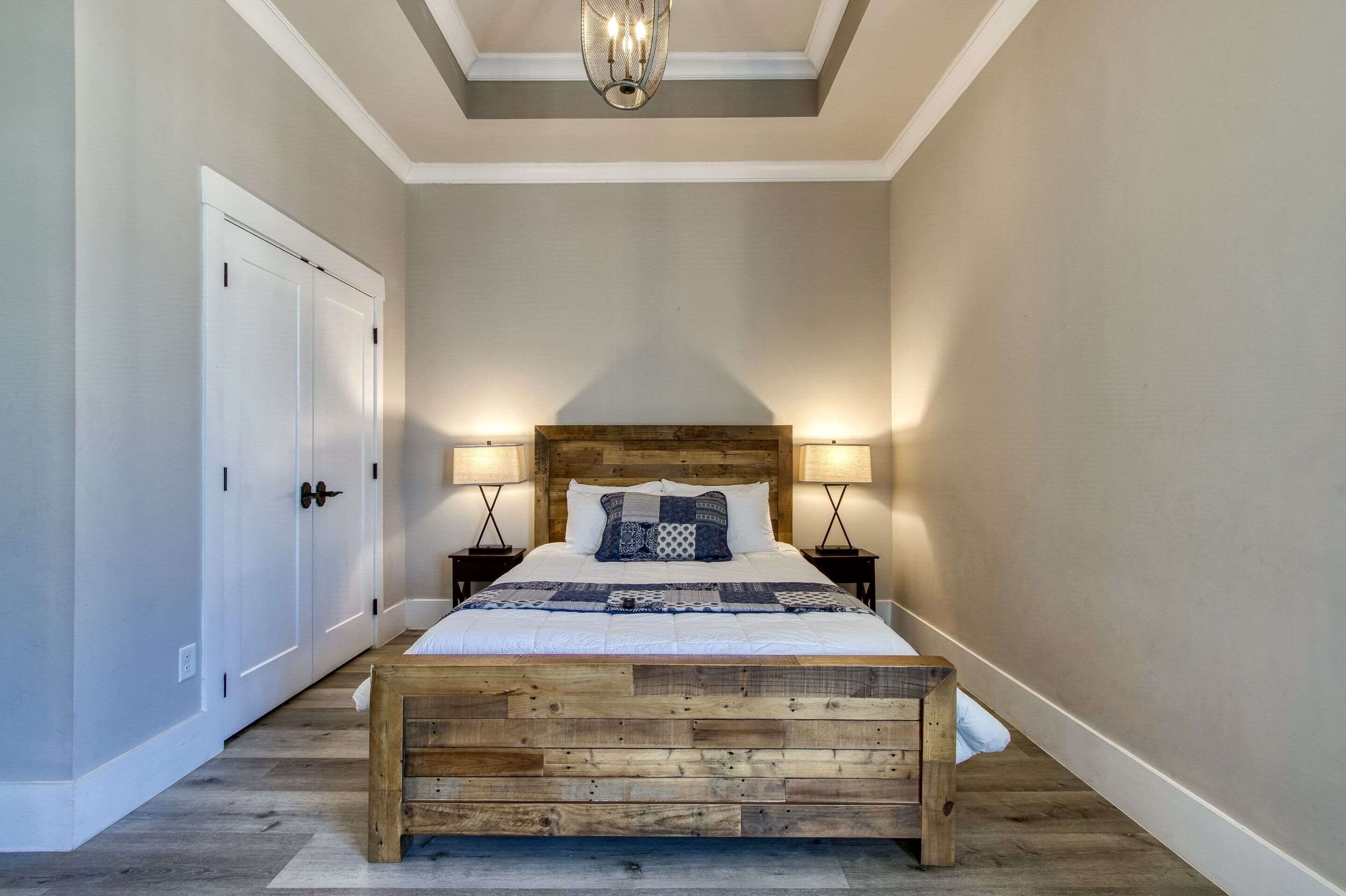 A bedroom with a wooden bed, two bedside lamps, a wooden headboard, and a white door.