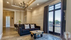 Una sala de estar moderna con un sofá oscuro, una mesa de centro de madera y un ventanal con cortinas.
