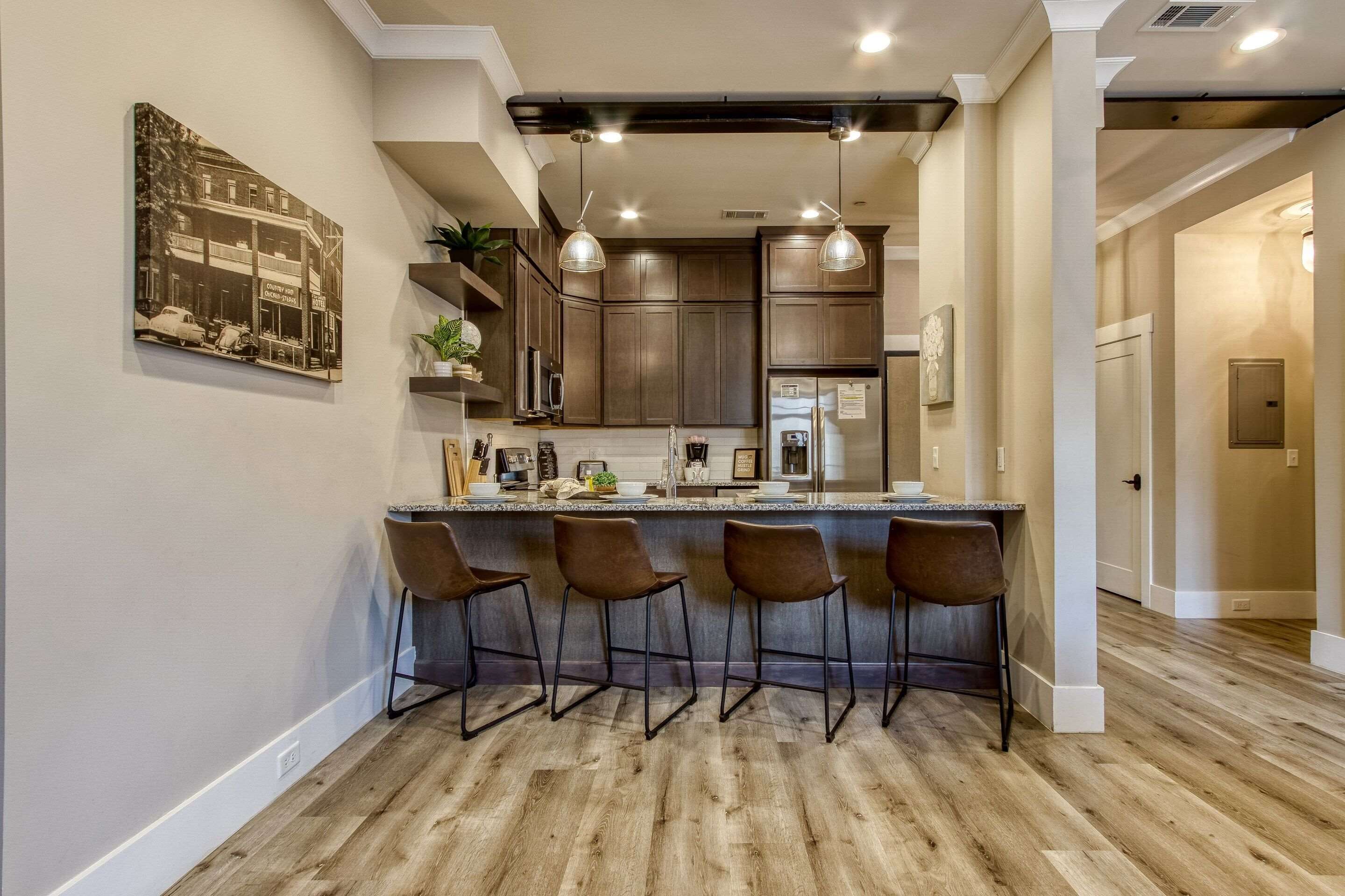 A modern kitchen with a bar area, wooden flooring, and pendant lighting.
