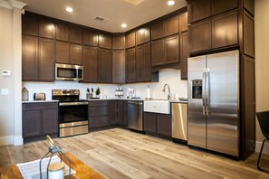 A modern kitchen with dark wood cabinets, stainless steel appliances, and a wooden floor. - The Historic Central Hotel, a New Hotel Collection Property (Sevierville)