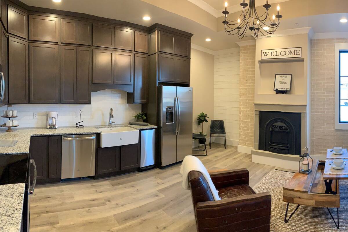 A modern kitchen with dark cabinets, stainless steel appliances, and a built-in dishwasher.