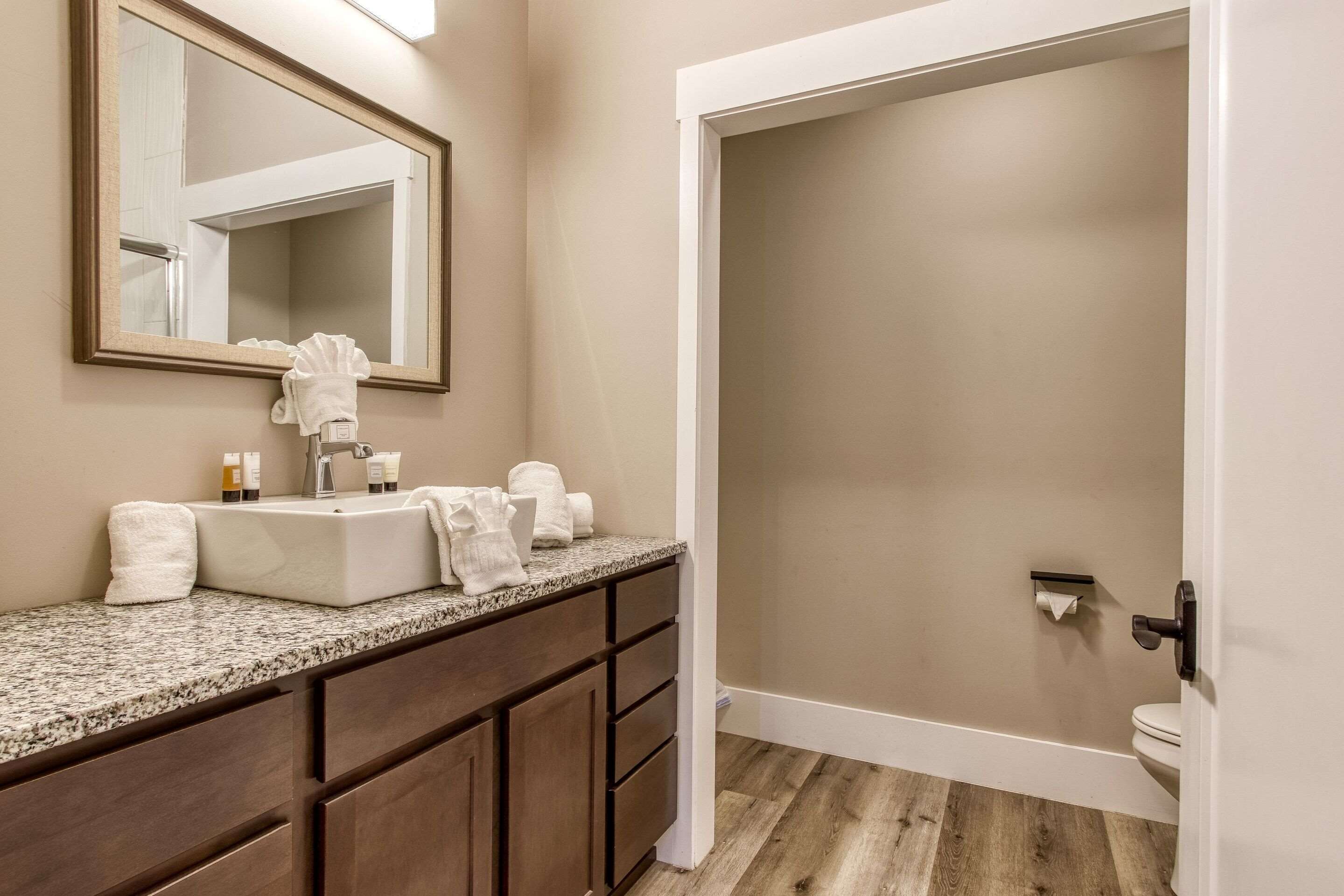 A bathroom with a sink, mirror, and a toilet.