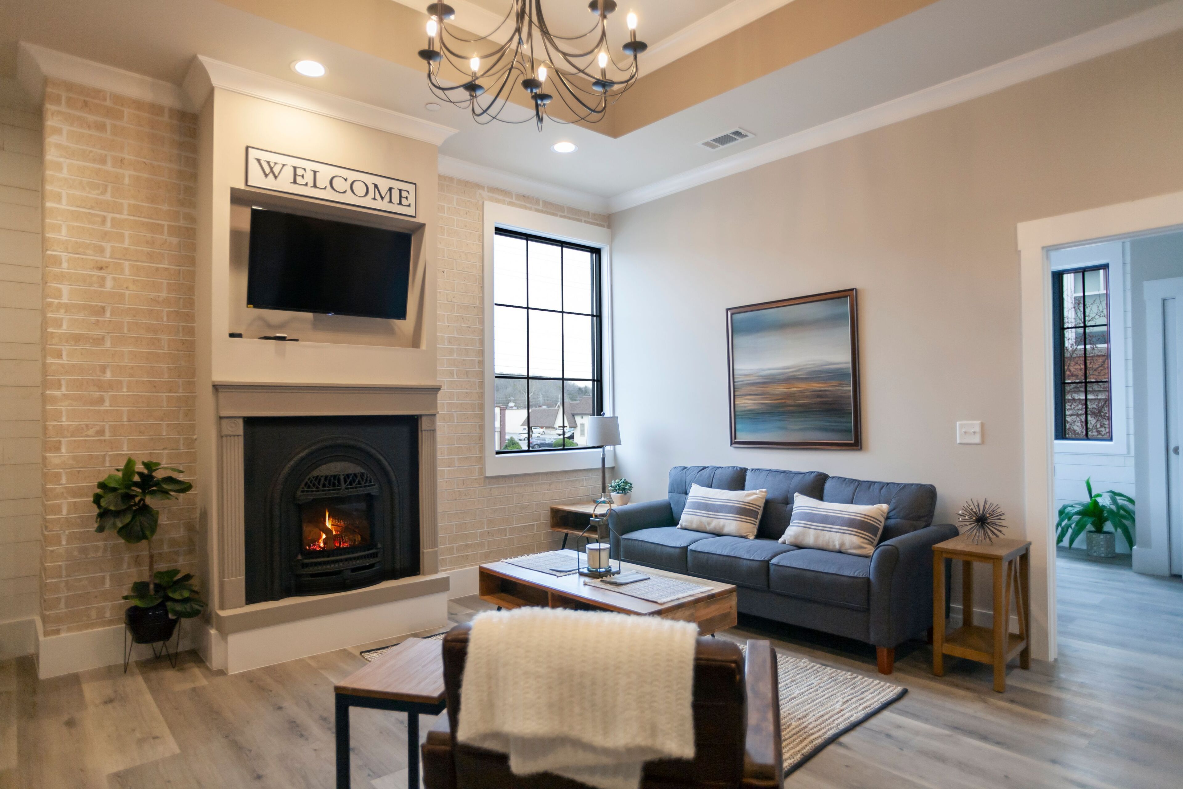 A living room with a fireplace, a sofa, a TV, and a chandelier.