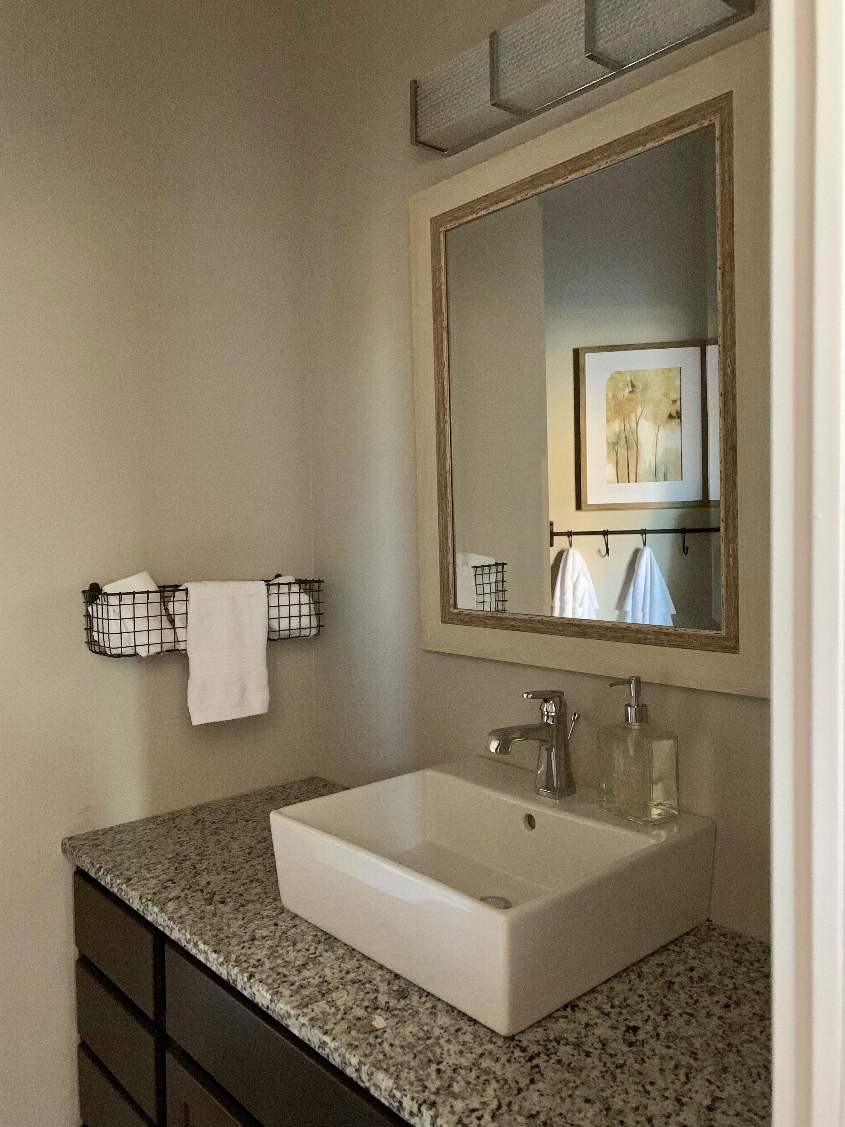 A bathroom with a white sink, a mirror, and a towel rack.