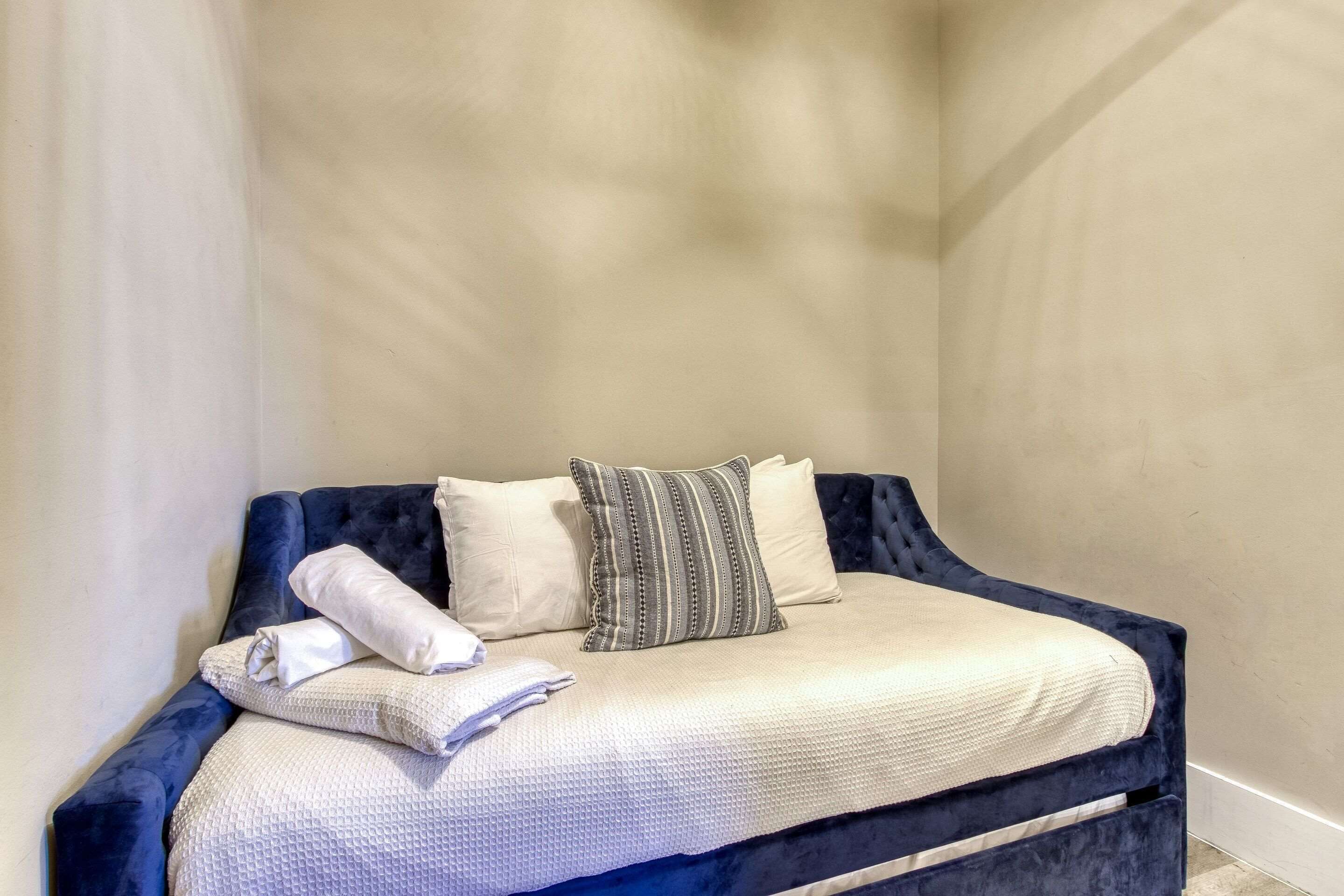 Ein ordentlich bezogenes Bett mit einer weiß-blauen Bettdecke, zwei Kissen und einer gefalteten Decke.