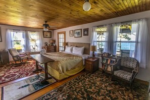 A bedroom with a bed, a chair, a table, a nightstand, and a bookshelf.